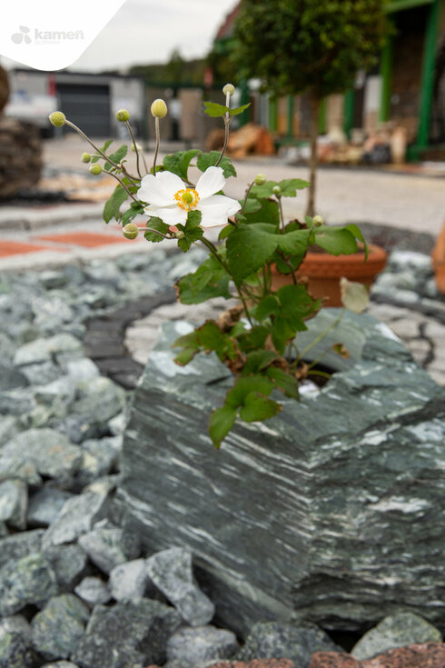 Kamenný kvetináč a dekoračné kamene v záhrade